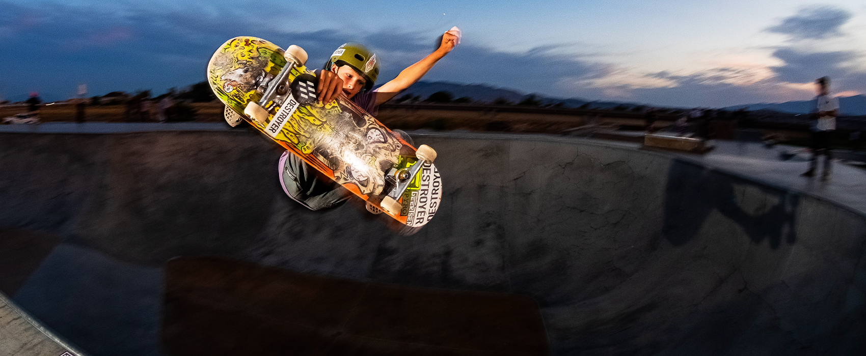 boy in skate bowl grabbing skateboard wearing destroyer certified helmet